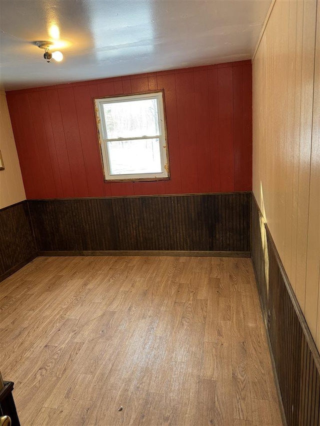 unfurnished room with light hardwood / wood-style flooring and wood walls