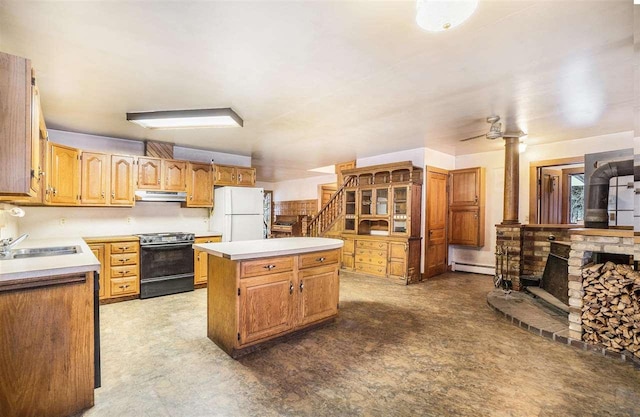 kitchen with sink, a wood stove, stainless steel stove, white fridge, and a kitchen island