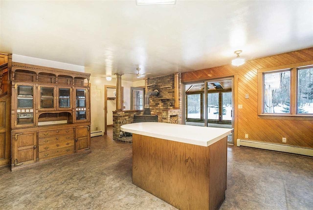 kitchen featuring wooden walls, a wood stove, and a baseboard heating unit