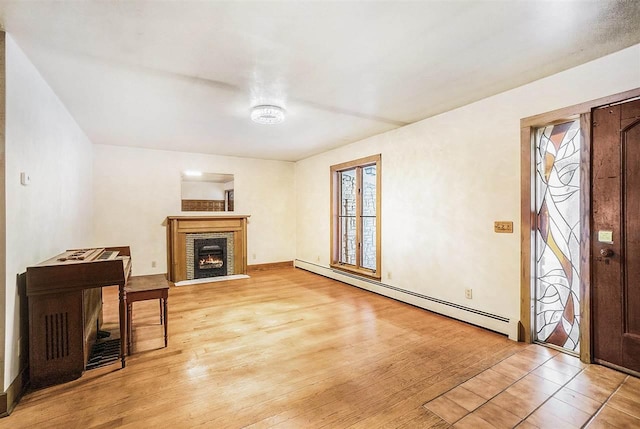 living room with baseboard heating, a fireplace, and light hardwood / wood-style floors