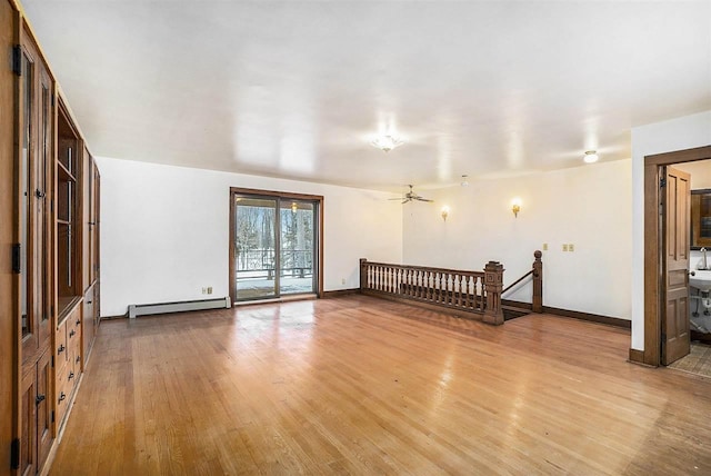 spare room with ceiling fan, light wood-type flooring, and a baseboard heating unit