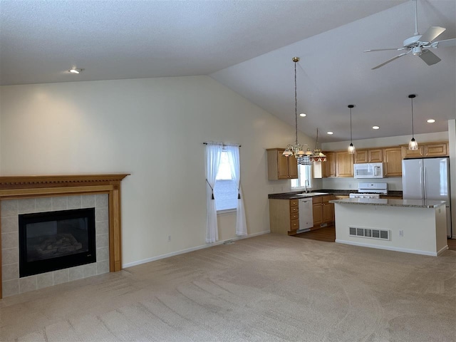 kitchen with sink, light carpet, a kitchen island, pendant lighting, and white appliances