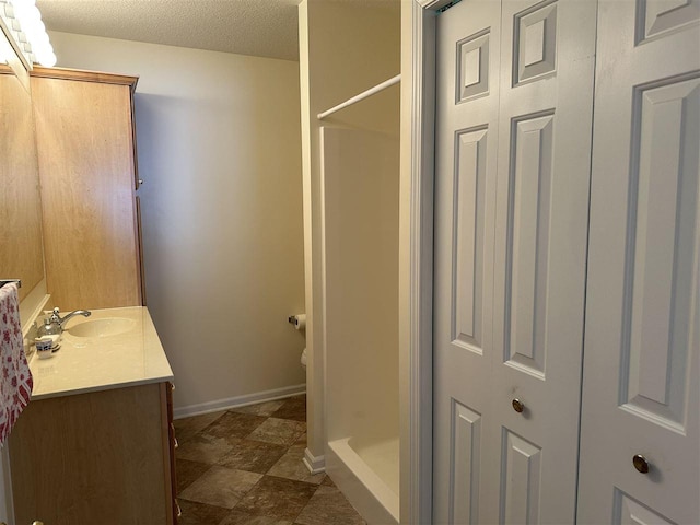 bathroom featuring vanity, toilet, a textured ceiling, and walk in shower