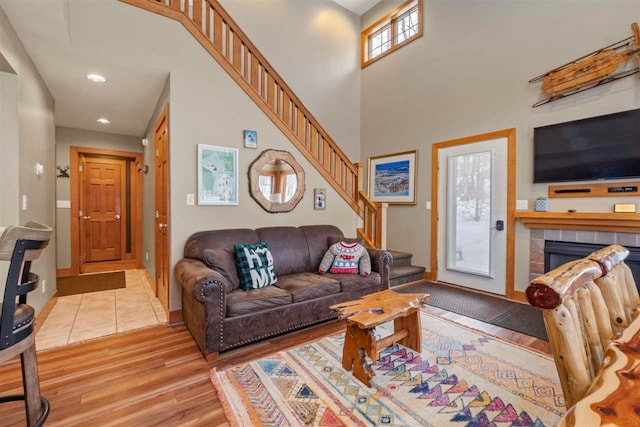 living room with a towering ceiling, a fireplace, and light hardwood / wood-style floors