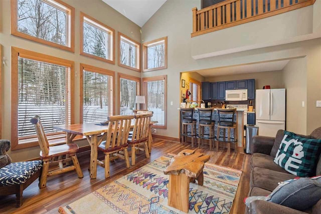 living room with plenty of natural light, high vaulted ceiling, and wood-type flooring