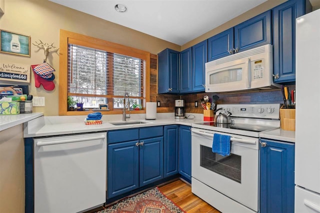 kitchen featuring sink, white appliances, light hardwood / wood-style flooring, and blue cabinetry