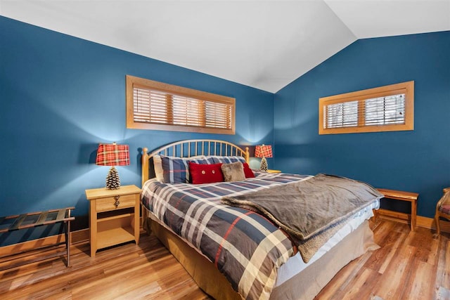 bedroom featuring multiple windows, vaulted ceiling, and light wood-type flooring