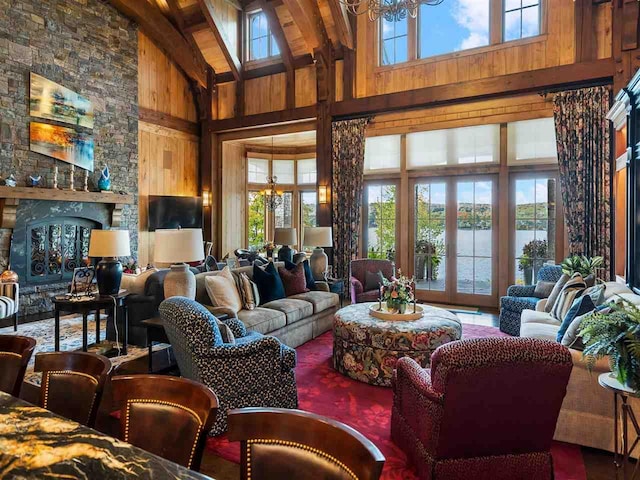 living room featuring an inviting chandelier, a wealth of natural light, wood walls, and a water view