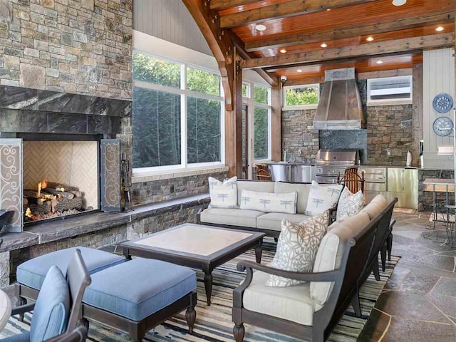 sunroom / solarium with beamed ceiling, wooden ceiling, and exterior fireplace