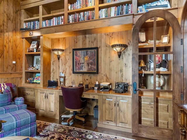 home office with built in desk, wood walls, and built in shelves