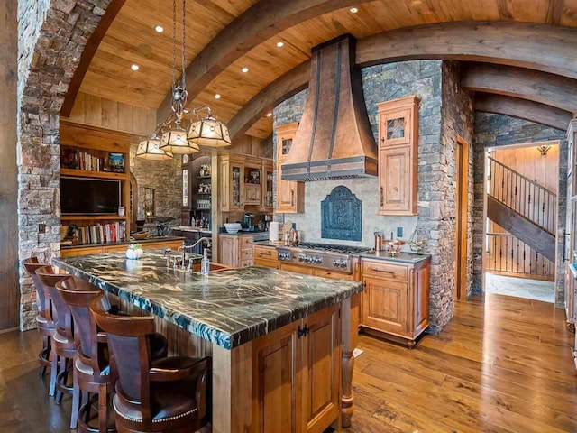 kitchen featuring wood ceiling, light hardwood / wood-style flooring, hanging light fixtures, custom range hood, and stainless steel gas stovetop