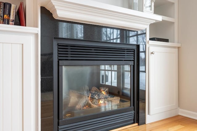 interior details featuring baseboards, a tiled fireplace, and wood finished floors