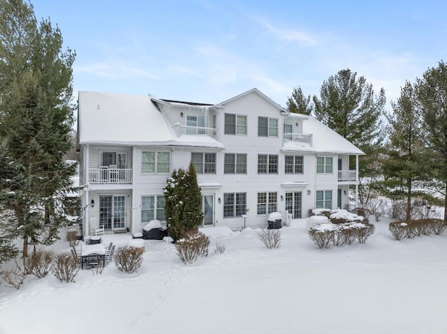 snow covered rear of property with a balcony