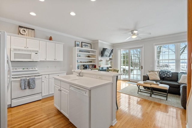 kitchen with white cabinets, light countertops, open floor plan, white appliances, and a kitchen island with sink