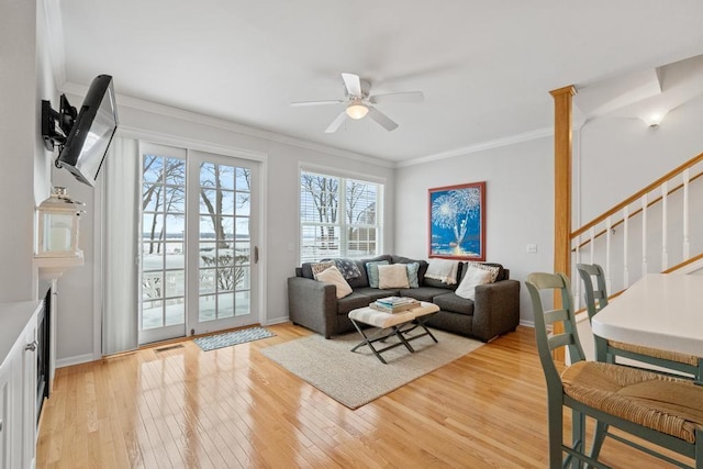 living area with stairs, crown molding, light wood-style floors, ceiling fan, and visible vents