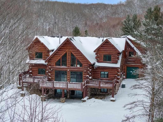 snow covered property with a garage and a deck