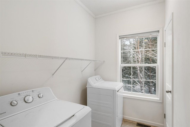 clothes washing area with crown molding, plenty of natural light, and separate washer and dryer