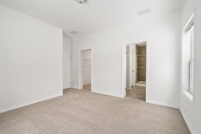 unfurnished bedroom with multiple windows, ornamental molding, a spacious closet, and light carpet