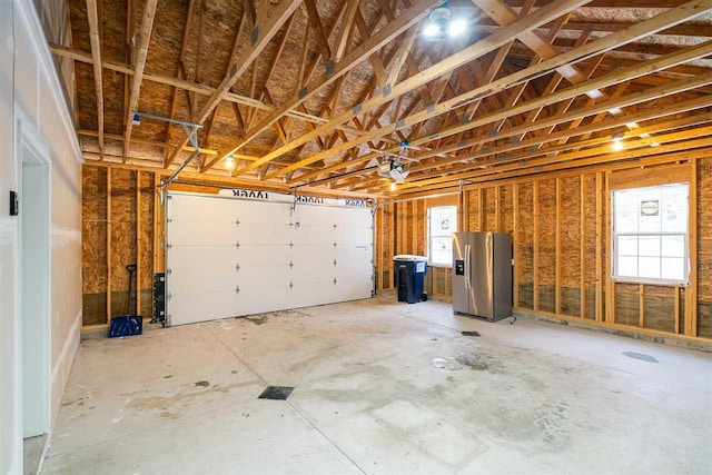 garage with stainless steel refrigerator with ice dispenser and a garage door opener