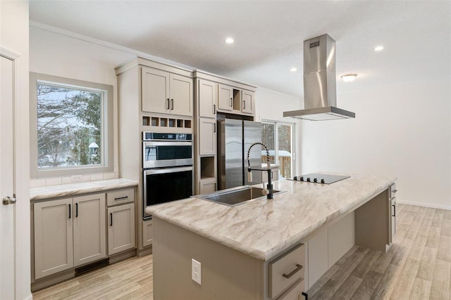 kitchen with island range hood, gray cabinetry, light stone counters, stainless steel appliances, and a center island with sink