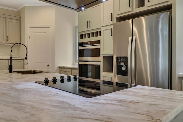 kitchen with appliances with stainless steel finishes, sink, ornamental molding, light stone countertops, and cream cabinetry