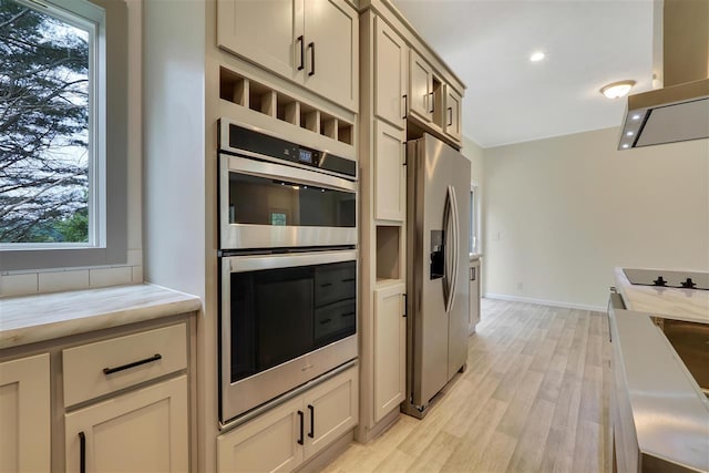 kitchen featuring cream cabinets, appliances with stainless steel finishes, light hardwood / wood-style floors, and island range hood