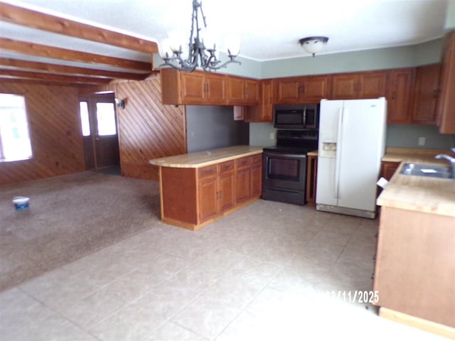 kitchen featuring wood walls, sink, hanging light fixtures, a notable chandelier, and stainless steel appliances