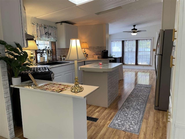 kitchen with a center island, stainless steel refrigerator, light hardwood / wood-style floors, sink, and white cabinets