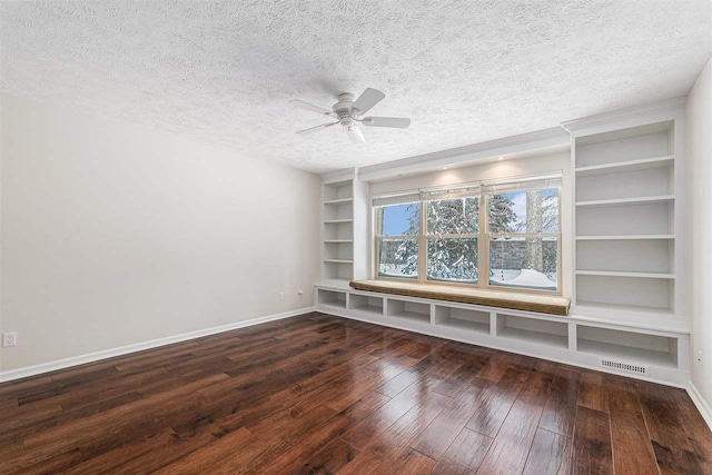 unfurnished room featuring ceiling fan, dark wood-type flooring, built in features, and a textured ceiling