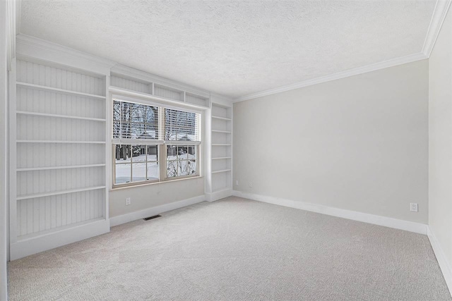 carpeted spare room with a textured ceiling, built in shelves, and crown molding