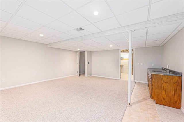 basement featuring sink, a paneled ceiling, and light carpet