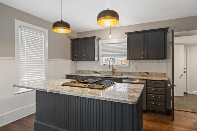 kitchen featuring a center island, dark wood-style flooring, decorative light fixtures, a sink, and light stone countertops