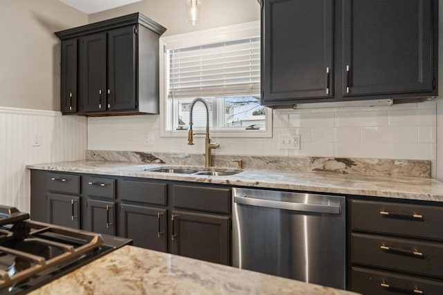 kitchen featuring wainscoting, a sink, gas cooktop, dark cabinets, and dishwasher