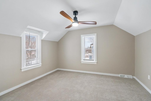 bonus room with lofted ceiling, light colored carpet, a ceiling fan, visible vents, and baseboards