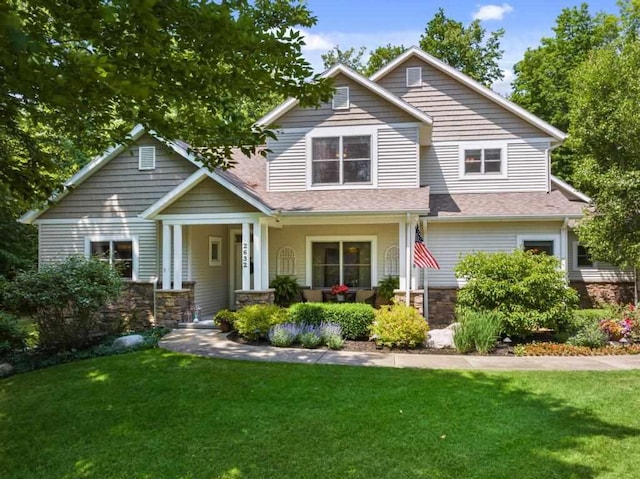 craftsman-style house featuring stone siding, a porch, and a front yard