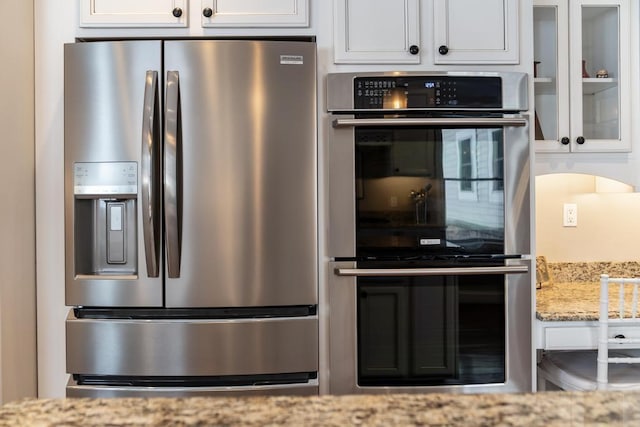 2632 Woodside Dr, Petoskey, MI 49770 - kitchen featuring appliances with stainless steel finishes, glass insert cabinets, light stone counters, and white cabinets