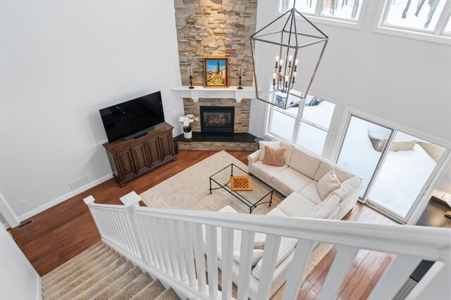 2632 Woodside Dr, Petoskey, MI 49770 - living area featuring baseboards, stairway, wood finished floors, a fireplace, and a notable chandelier