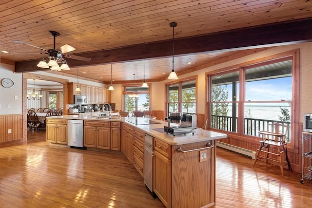 kitchen featuring a wainscoted wall, appliances with stainless steel finishes, light countertops, a baseboard heating unit, and pendant lighting