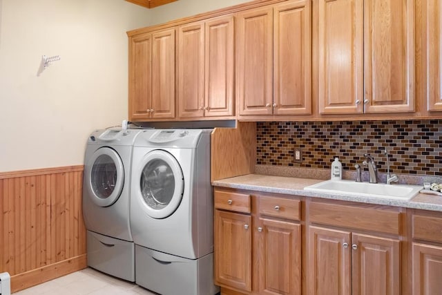 laundry room featuring cabinet space, a wainscoted wall, independent washer and dryer, wood walls, and a sink