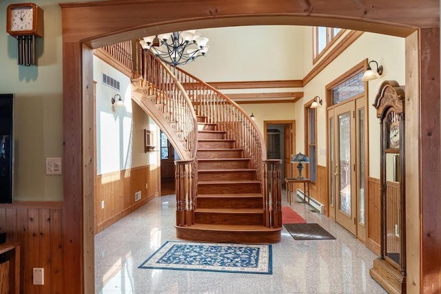 staircase featuring wood walls, visible vents, a wealth of natural light, and wainscoting