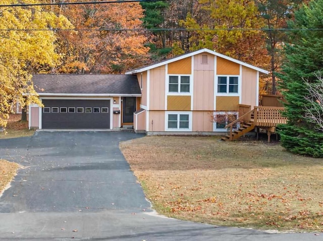 split level home featuring a garage, a front yard, driveway, and stairway