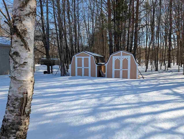 snow covered structure with a shed and an outdoor structure