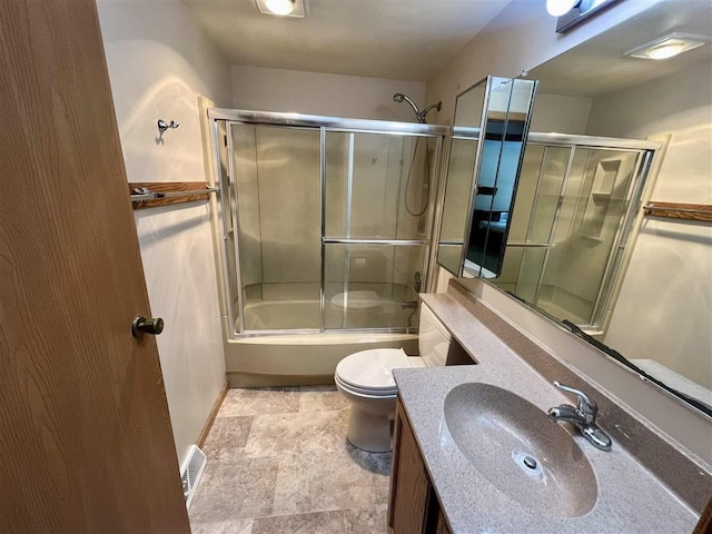 bathroom featuring bath / shower combo with glass door, visible vents, toilet, vanity, and baseboards