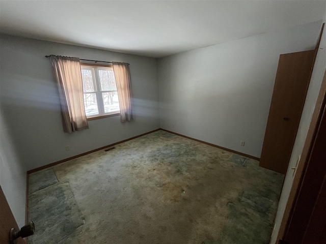 carpeted spare room featuring visible vents and baseboards