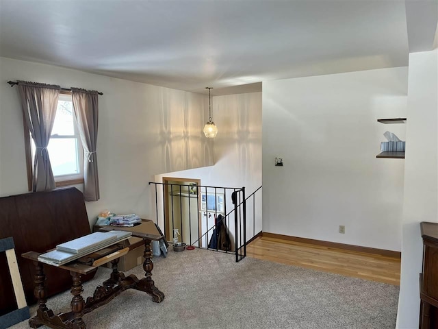 carpeted office space with wood finished floors and baseboards