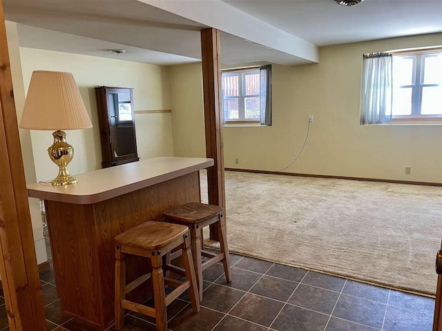 bar featuring a dry bar, dark tile patterned floors, dark carpet, and baseboards