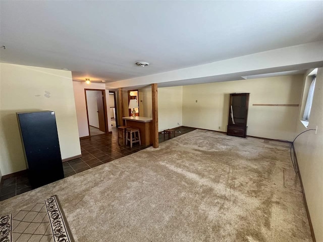 empty room featuring dark tile patterned floors, dark carpet, and baseboards