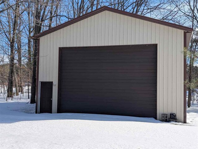 snow covered garage with a detached garage