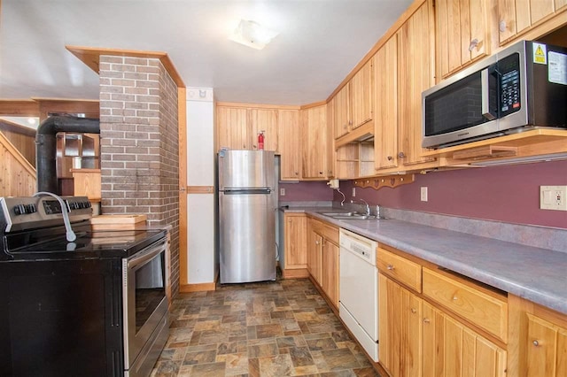 kitchen featuring light brown cabinets, a sink, light countertops, appliances with stainless steel finishes, and stone finish flooring