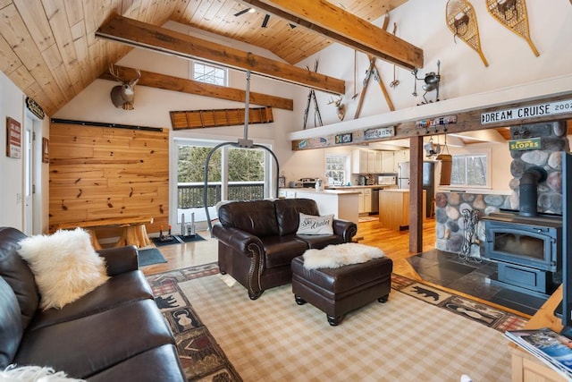 living room with a wood stove, wooden ceiling, high vaulted ceiling, and beamed ceiling